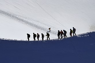 A group of mountaineers runs across a snow-covered mountain ridge, Aiguille du Midi,