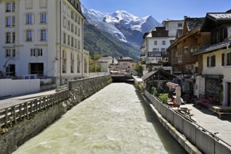 Glacier river Arve flows through the city, with the snow-capped Mont-Blanc mountain range behind,