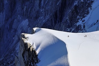 A group of mountaineers runs across a snow-covered mountain, Aiguille du Midi, Chamonix-Mont-Blanc,