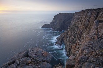 Long exposure shows sunset over the cliffs of Cape Raoul. Golden light hits the sea and colors the