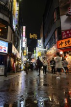 Busy pedestrian zone with many shopping centers and stores, illuminated with lots of neon signs at