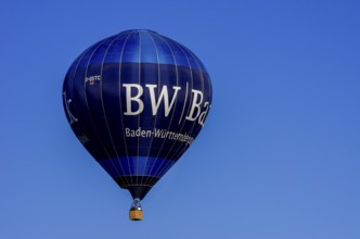 A hot air balloon, registration D-OSTC, rises into the air as part of an air show at the Rossfeld