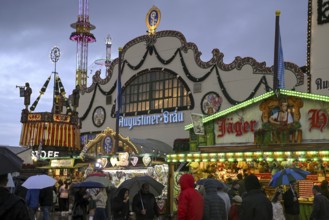 Oktoberfest visitors with umbrellas, rainy meadows, Augustiner festival tent, Munich, Bavaria,