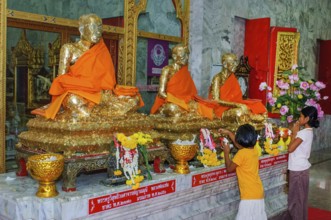 Buddhist believers Buddhists pray making offerings to statues of Buddhist monks covered with gold