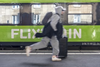 Flixtrain train on track 2 in Essen main station, passenger runs with luggage to reach his train,