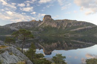 Morning dream over the quiet Steigtindvatnet near Bodø. Pine forest on the rock face at sunrise