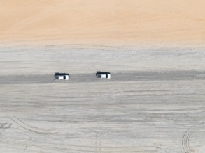 Aerial view, top-down view, two off-road cars driving on a road in arid countryside, Botswana