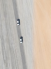 Aerial view, top-down view, two off-road cars driving on a road in arid countryside, Botswana