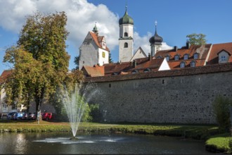Trench pond with water fountain, city wall, church towers and water tower at the back, Isny,