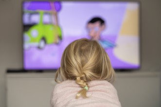 Child, girl, 4 years old, blonde, lying on sofa, watching TV, watching television, in front of