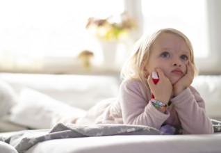 Child, girl, 4 years, blonde, lying on sofa, watching TV, watching television, watching television,