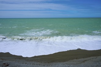 Green sea with waves, clear sky and pebble beach, Tuhawaiki Point Lighthouse or Jack's Point