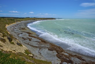Long stretch of coastline with wavy sea and blue sky, Tuhawaiki Point Lighthouse or Jack's Point