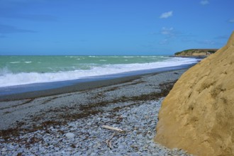 Rocky beach with waves and blue sky, Tuhawaiki Point Lighthouse or Jack's Point Lighthouse,