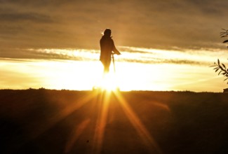 E-scooter drivers ride across a dike on the island of Fehmarn at sunset, 13.10.2025, Fehmarn,