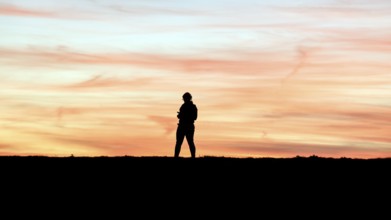 Woman with cell phone running on a dike at sunset, Fehmarn Island, 13.10.2025, Fehmarn,