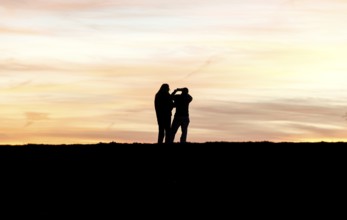 Walkers with mobile phone at sunset on a dike, Fehmarn island, 13.10.2025, Fehmarn,