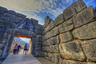 HDR, group of visitors passes through a huge stone gate, lion gate, Mycenae, archaeological site,