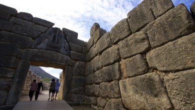 Group of visitors pass through a huge stone gate, lion gate, Mycenae, archaeological site, UNESCO