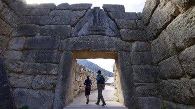 Couple walking through a huge stone gate, lion gate, Mycenae, archaeological site, UNESCO World