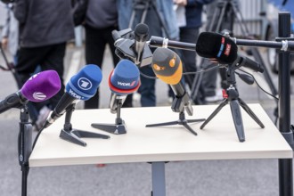 Microphones from various radio stations, television stations, standing on the table, at a press