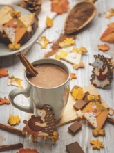 Cup of hot chocolate with cinnamon stick and autumn animal decorations