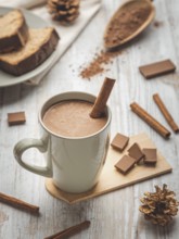 A cup of hot chocolate with cinnamon stick surrounded by cocoa powder and cake
