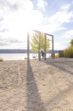 Lakeside swing with sun and long shade on the sand, Überlingen, Lake Constance, Germany