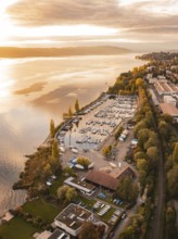 A harbor with anchored boats at sunset, surrounded by an urban landscape in autumn, Überlingen,