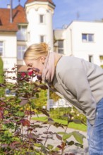 Woman with red hair enjoying the scent of flowers in autumn garden, Überlingen, Lake Constance,