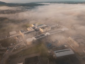 Building in an industrial area seen from above in fog, surrounded by landscape at daybreak, new