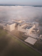 Building complex in dreamy fog, taken from the air early in the morning with blurred colors, new