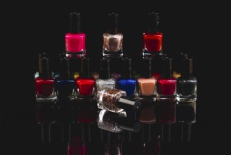 Colourful nail polish bottles with reflections against a black background