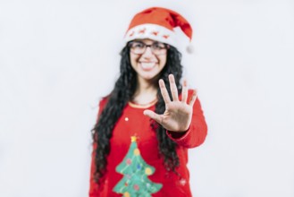 Smiling girl in Christmas sweater counting five. Funny girl in a Christmas hat counting five,