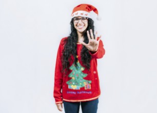 Funny girl in Christmas hat counting five, isolated. Smiling girl in Christmas sweater counting