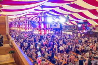 Fully occupied marquee with people in traditional costumes and colourful decorations, Cannstatter