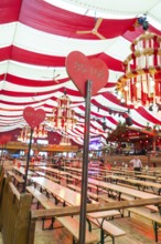Festively decorated marquee with red blankets, wooden benches and heart-shaped sign, Cannstatter