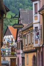 Alley with half-timbered houses and guild signs in the old town of Kaysersberg