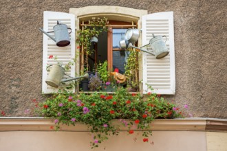 Decorated window with watering cans in Ribeauvillè