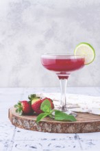Refreshing cocktail in an elegant glass with lime and strawberries, sunshine, no people