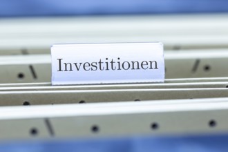 (Photomontage) Sign with the inscription INVESTMENTS on a suspension file folder