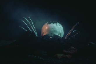 A skull with skeletonised hands bursts out of the earth in the moonlight, Halloween