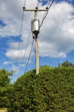 Electricity transformer, high voltage transmission wires, internet, telephone cables attached to