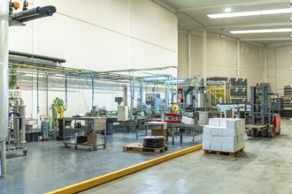 Industrial brewery interior featuring automated production lines, bottling machinery, tanks, pipes,