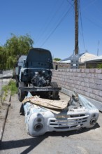 A dismantled old lorry with visible engine in front of a wall under a blue sky, engine repair,