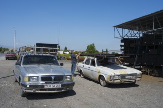 Two rusty old cars, a man in the background, mid-range cars GAZ-3110 Volga and GAZ-24 Volga,