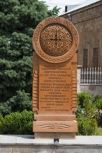 An elaborately engraved stone khachkar with complex ornaments and Armenian characters, surrounded
