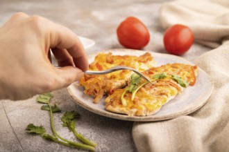 Baked chicken meat with cheese and tomatoes with hand on brown concrete background and linen