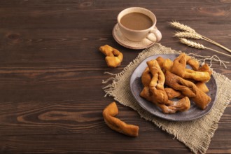 Crunchy biscuit Brushwood cookies sprinkled with powdered sugar on brown wooden background and