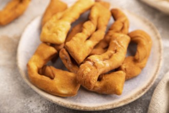Crunchy biscuit Brushwood cookies sprinkled with powdered sugar on brown concrete background and